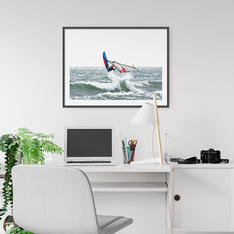 Fartfylld windsurfing-bild i svart ram på hemmakontor.